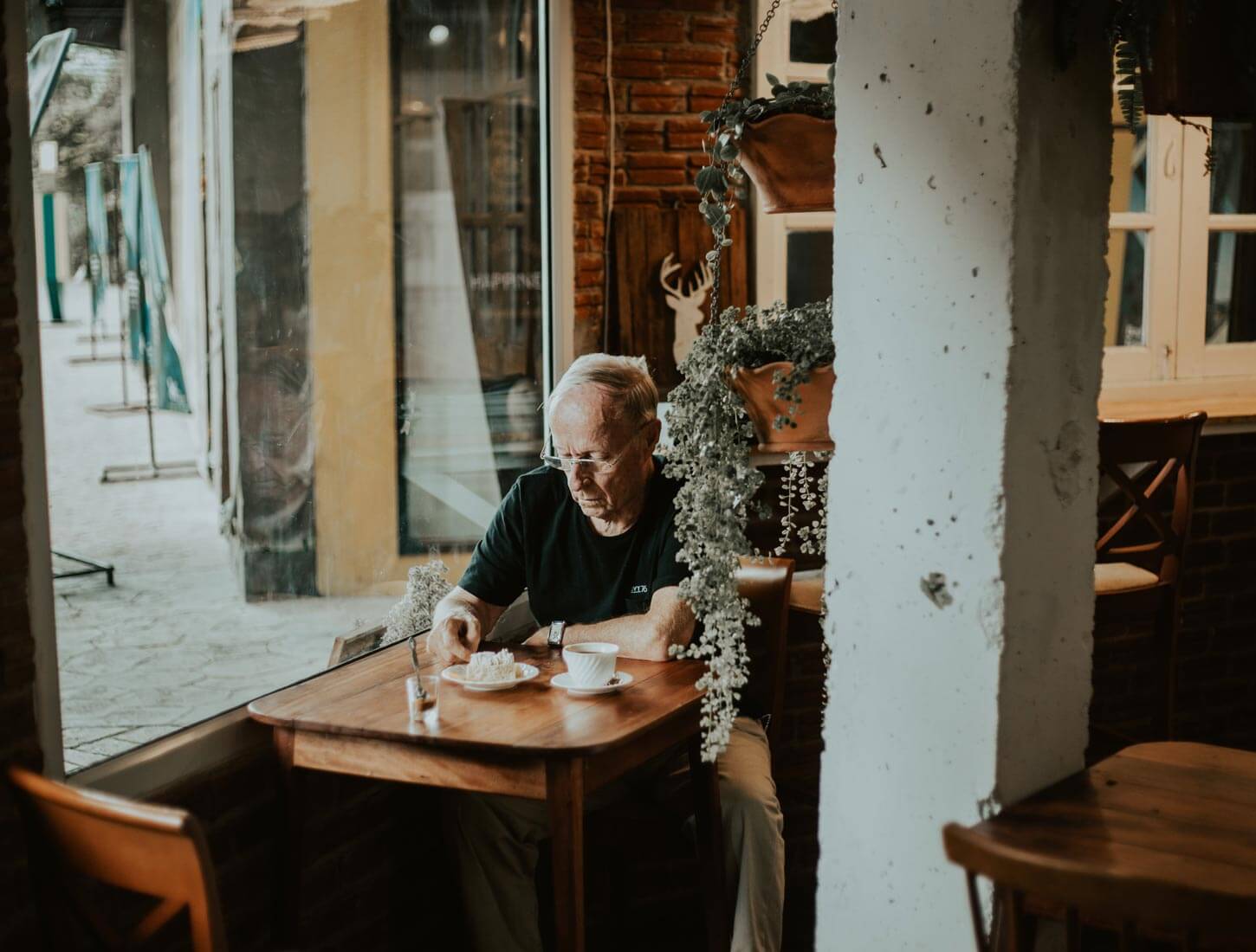 Ein alter Mann mit Alzheimer sitzt in einem Café und trinkt Kaffee