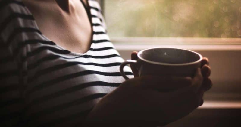 Eine Frau hält eine Tasse Kaffe in der Hand, die sie nicht trinken darf, weil sie einen Koffeinentzug macht